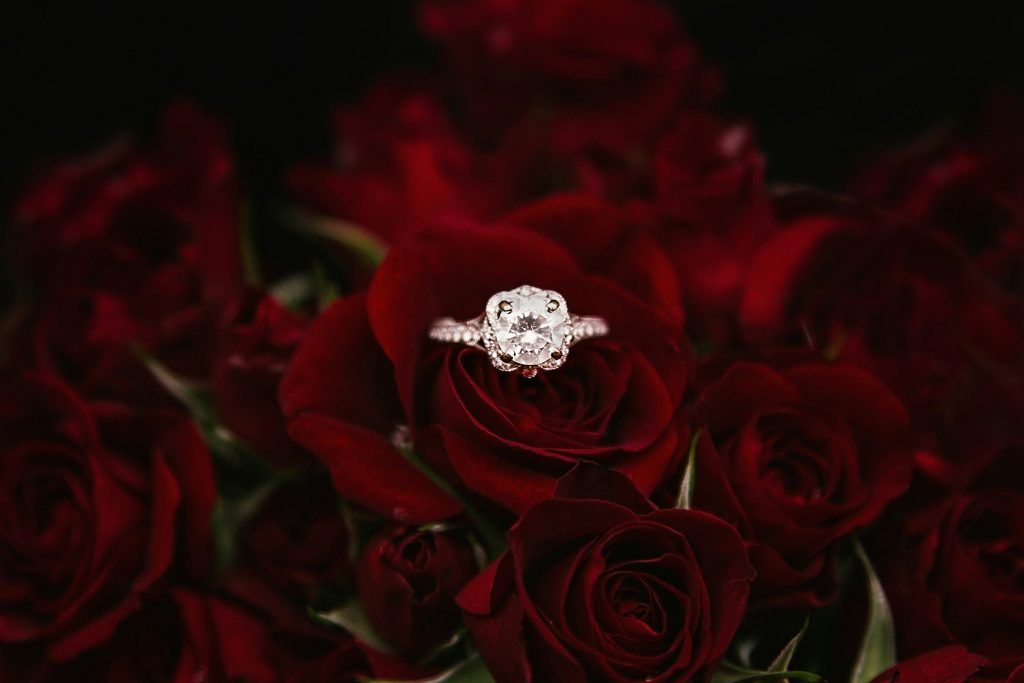 A silver ring with a diamond in the center lying among the tree’s flowers.