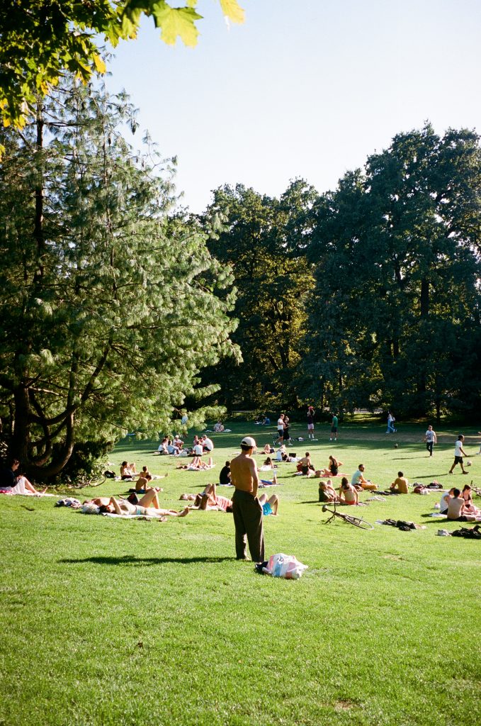 A picnic on the green grass, with lots of people lying down and eating.